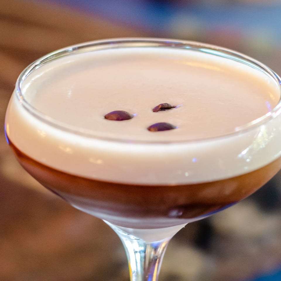 Creamy espresso martini topped with three coffee beans in a chilled coupe glass.